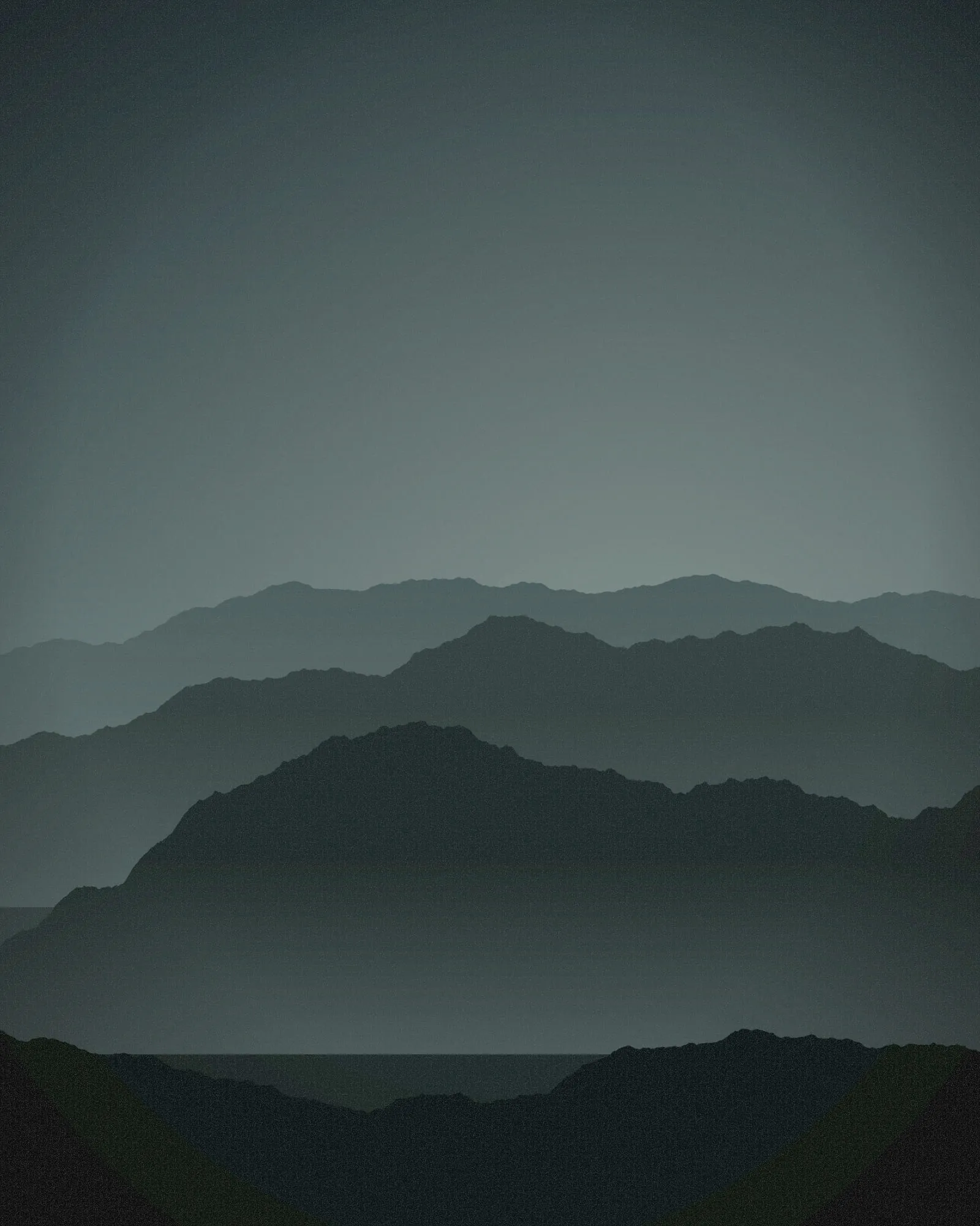 Ridges of pine-covered hills fading into grey-green fog, each layer paler than the one before.